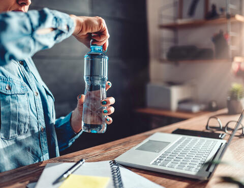 woman opening bottle at her desk